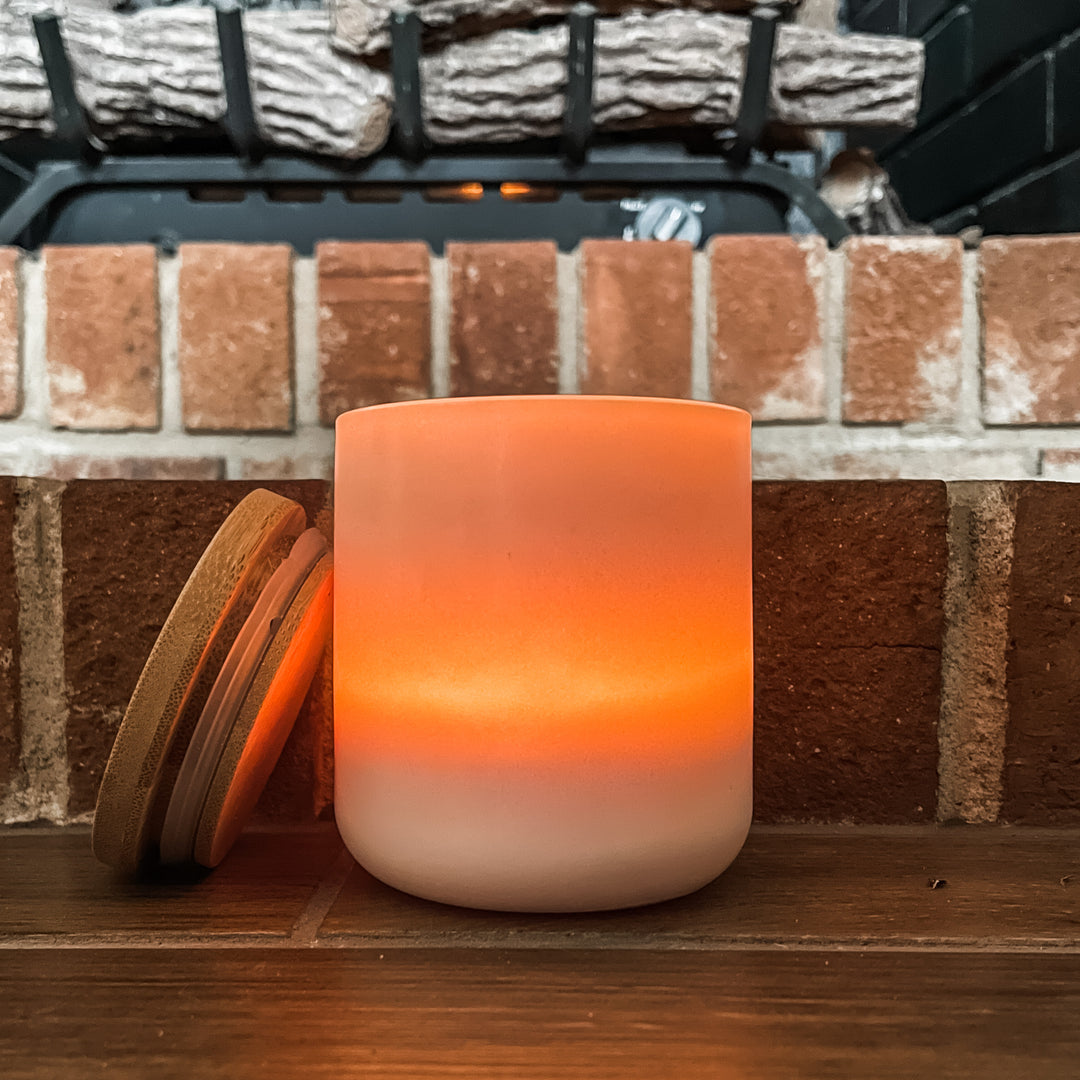 glowing candle in white ceramic jar